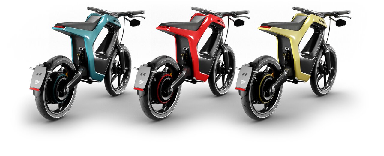 Drei E-Bikes in Türkis, Rot und Gelb stehen nebeneinander vor weißem Hintergrund.