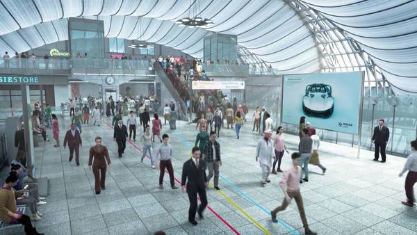 Eine Menschenmenge bewegt sich durch eine helle Bahnhofshalle mit Geschäften und Infotafeln.