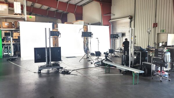 Ein Studio mit hellen Leuchtwänden, Kameras und Technikaufbau wird für Dreharbeiten vorbereitet.