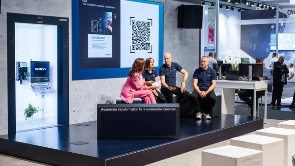 Vier Personen sitzen auf einer Bühne und diskutieren vor einem großen Bildschirm mit QR-Code und Siemens-Logo.