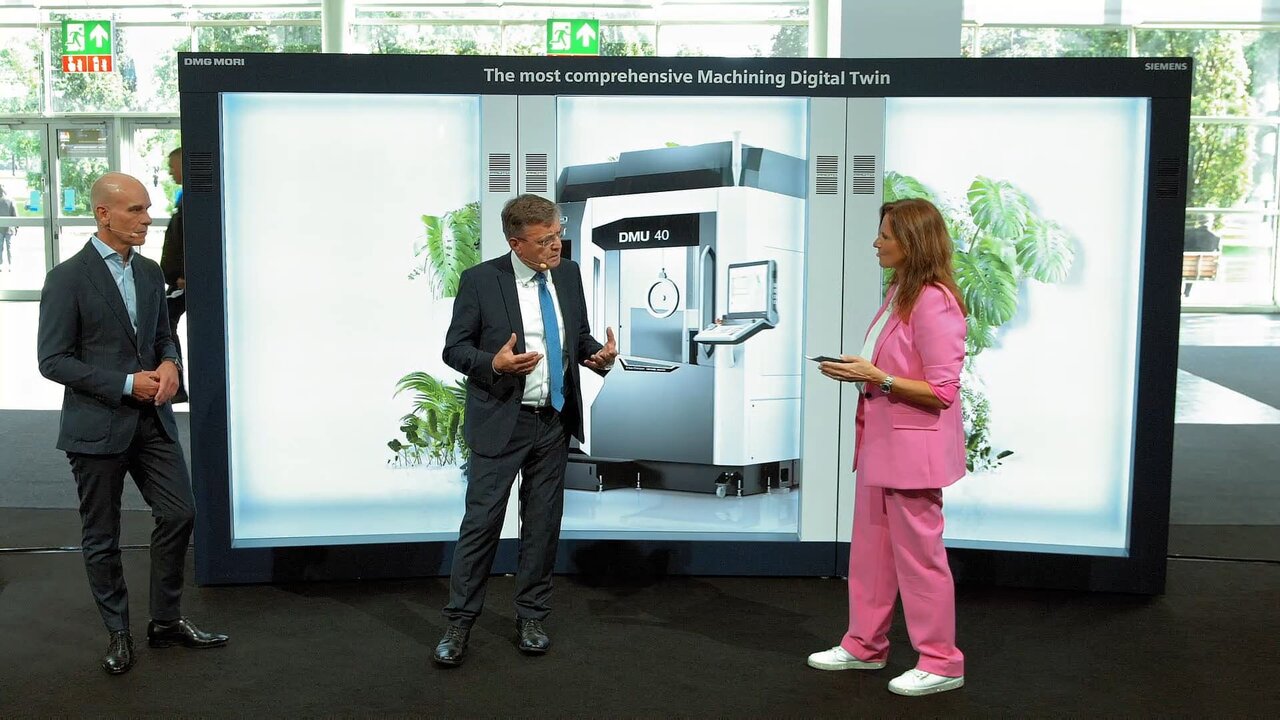 Zwei Männer und eine Frau sprechen vor einer Holobox, in der eine Industriemaschine zu sehen ist.