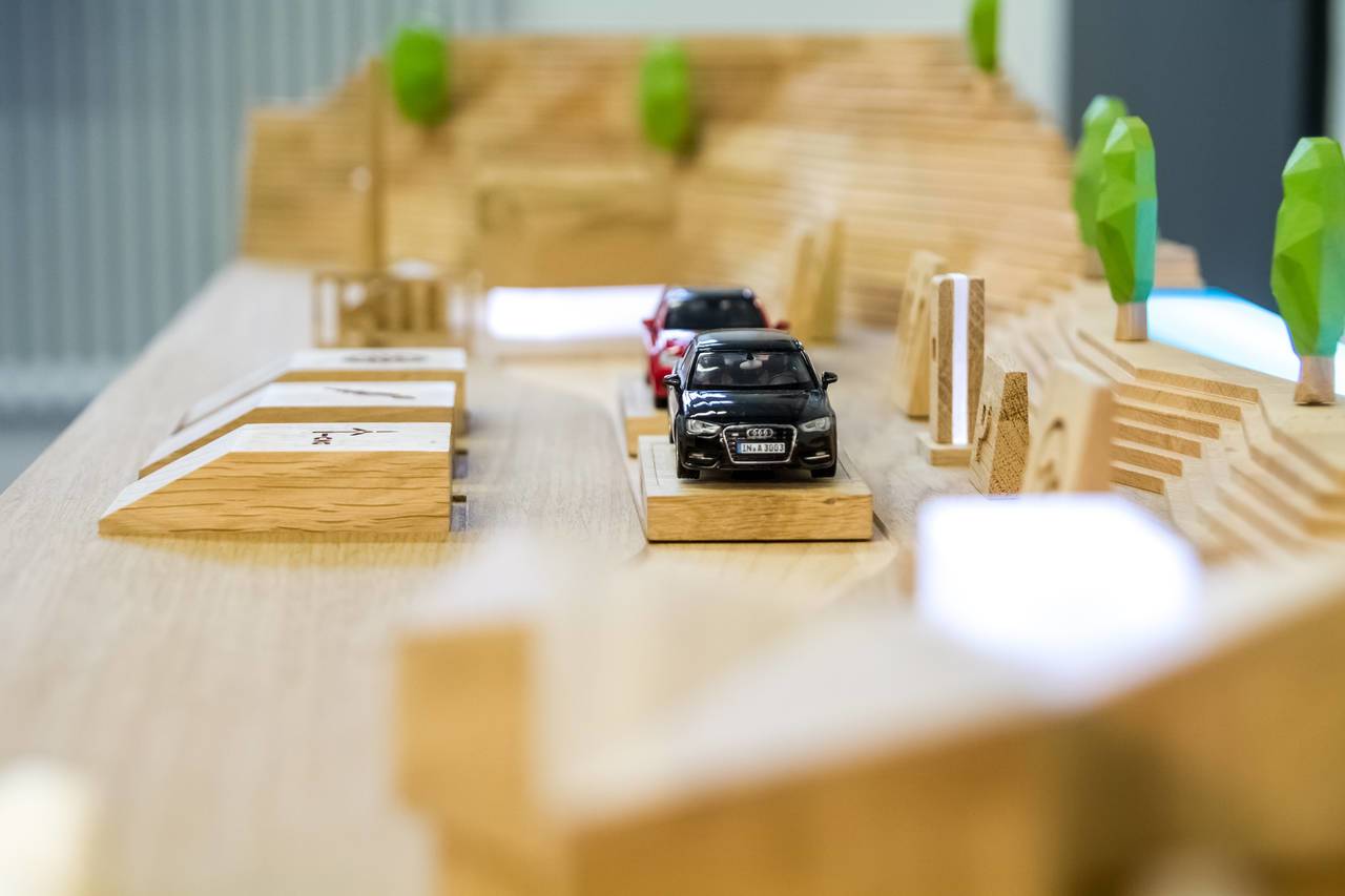 Modellstraße mit schwarzem und rotem Auto auf Holzuntergrund.