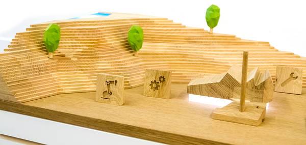 Holzlandschaft mit Symbolklötzen und stilisierten Bäumen.