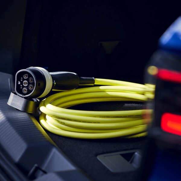 Gelbes Ladekabel eines E-Autos liegt aufgerollt im Kofferraum.
