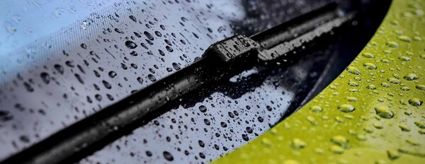 Scheibenwischer auf nasser Windschutzscheibe mit Wassertropfen.