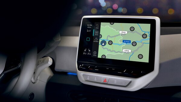 Navigationssystem im Auto zeigt Route mit mehreren VW-Ladestationen.