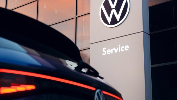 Rückansicht eines VW vor einem Gebäude mit VW-Service-Schild.