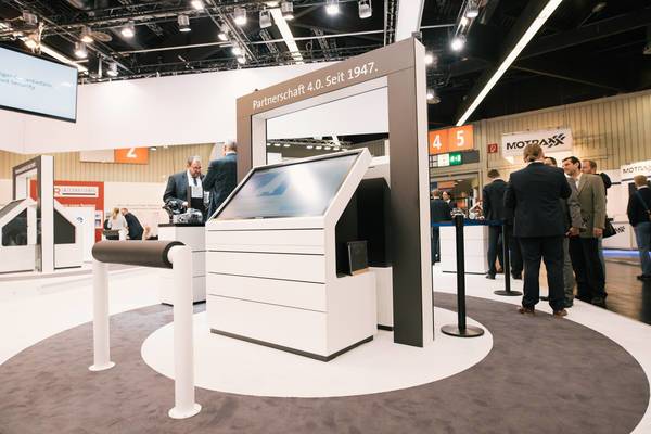 Interaktive Lenze-Station mit großem Bildschirm und Aufschrift „Partnerschaft 4.0. Seit 1947.“ im Messeumfeld.