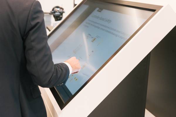 Hand eines Mannes bedient technischen Touchscreen mit schematischer Darstellung.