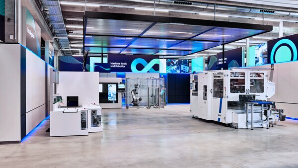Heller Showroom mit industriellen Maschinen, Robotikzelle im Hintergrund und digitalen Informationsflächen an den Wänden.
