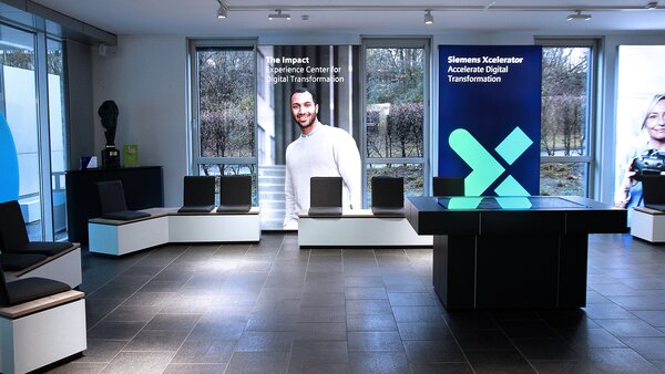 Moderner Empfangsbereich mit Sitzmöbeln und digitalen Bannern, die Transformation und Technologie thematisieren.