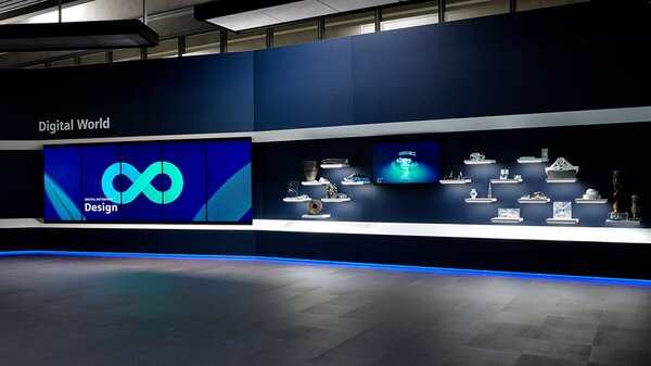 Ausstellungswand mit beleuchteten Produktmodellen und großem Display, das „Digital World“ und „Design“ präsentiert.