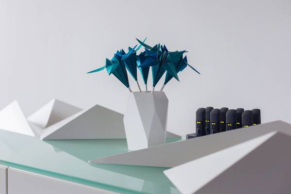 Virtuelles Designobjekt mit Origami-Blumen in Vase, daneben schwarze Objekte mit gelben Leuchtpunkten.