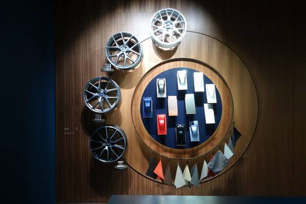 Felgen, Farbmuster und Stoffproben kreisförmig an einer Holzwand präsentiert.