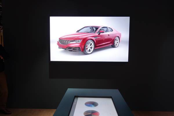 Großaufnahme eines Monitors, auf dem ein rotes Auto vor weißem Grund zu sehen ist.