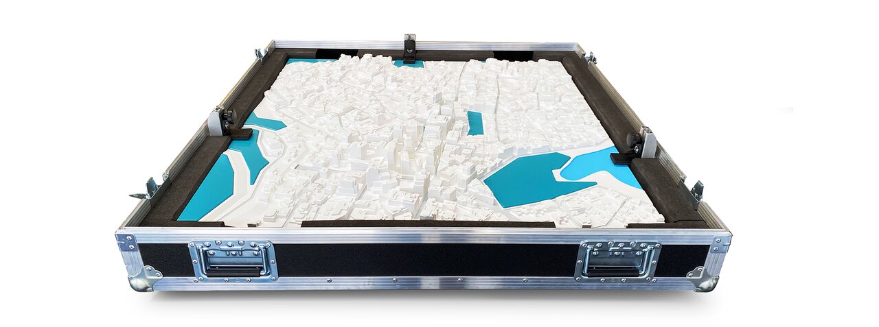 Physisches Stadtmodell mit blauen Wasserflächen sicher verpackt in einem Koffer.