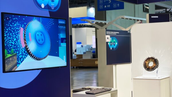 Messestand mit Monitor, der eine digitale 3D-Visualisierung eines Zahnrads zeigt, daneben das reale Zahnrad auf einem Sockel.