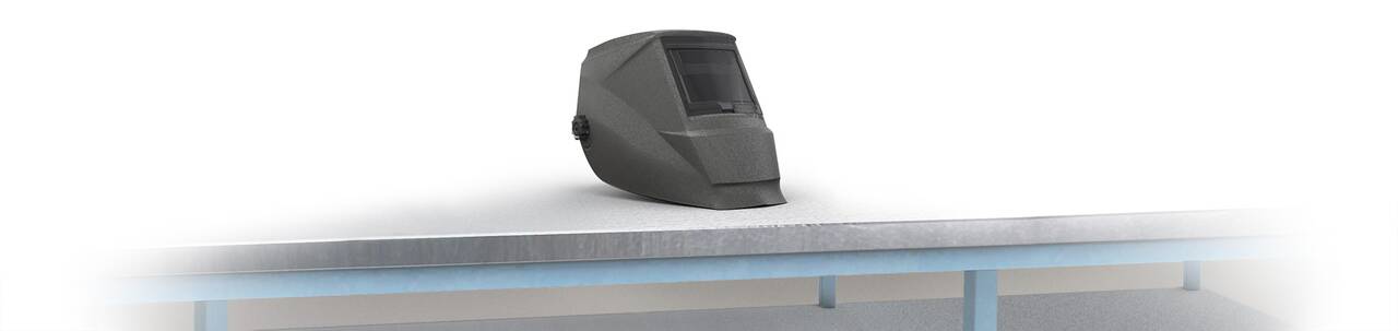 Schweißhelm liegt mittig auf einer Werkbank – klar vor weißem Hintergrund platziert.