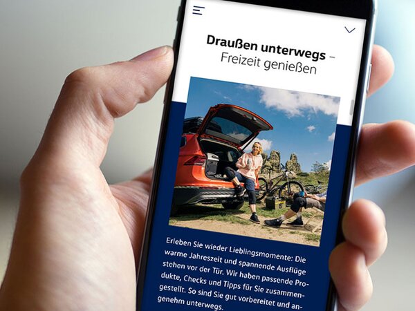 Hand hält Smartphone mit VW-Service-Seite.